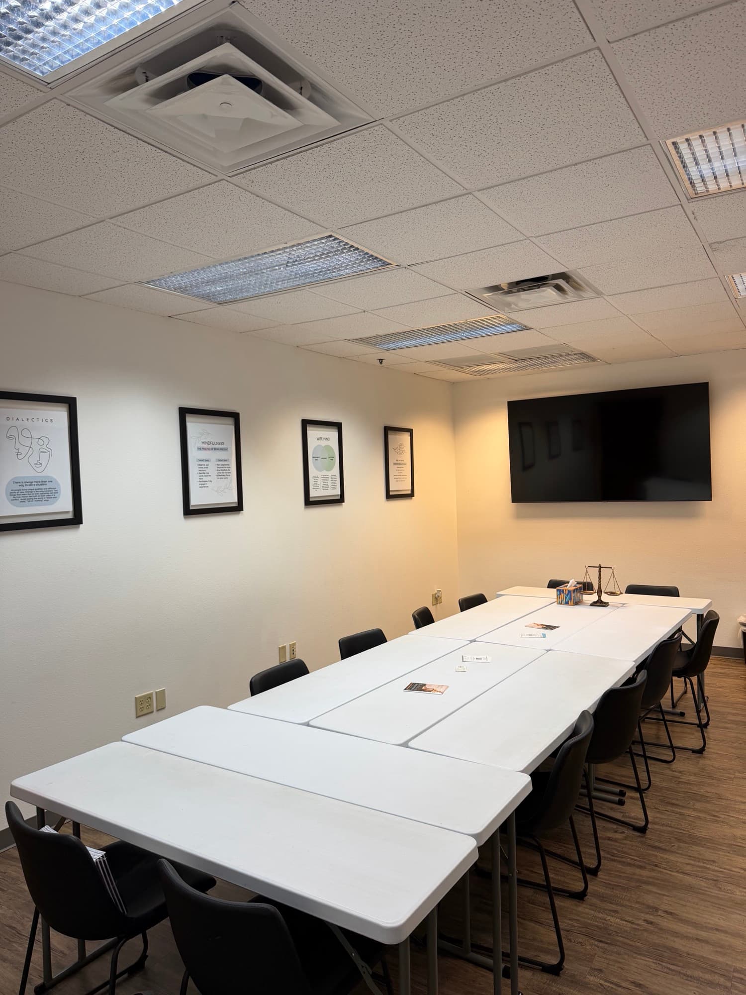 Group room with long tables and a wall-mounted TV for trainings and groups
