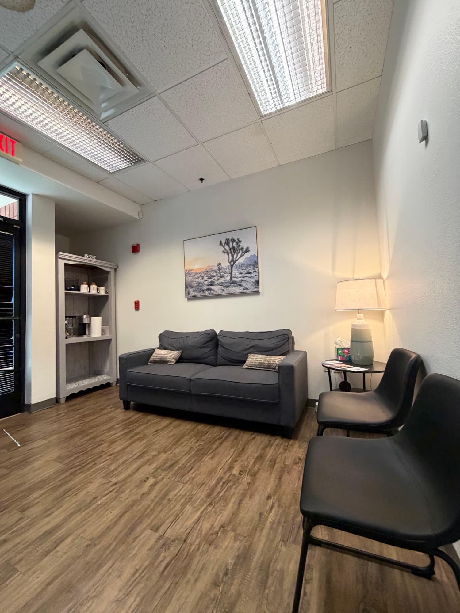 Waiting area with a couch, coffee station, and desert landscape art