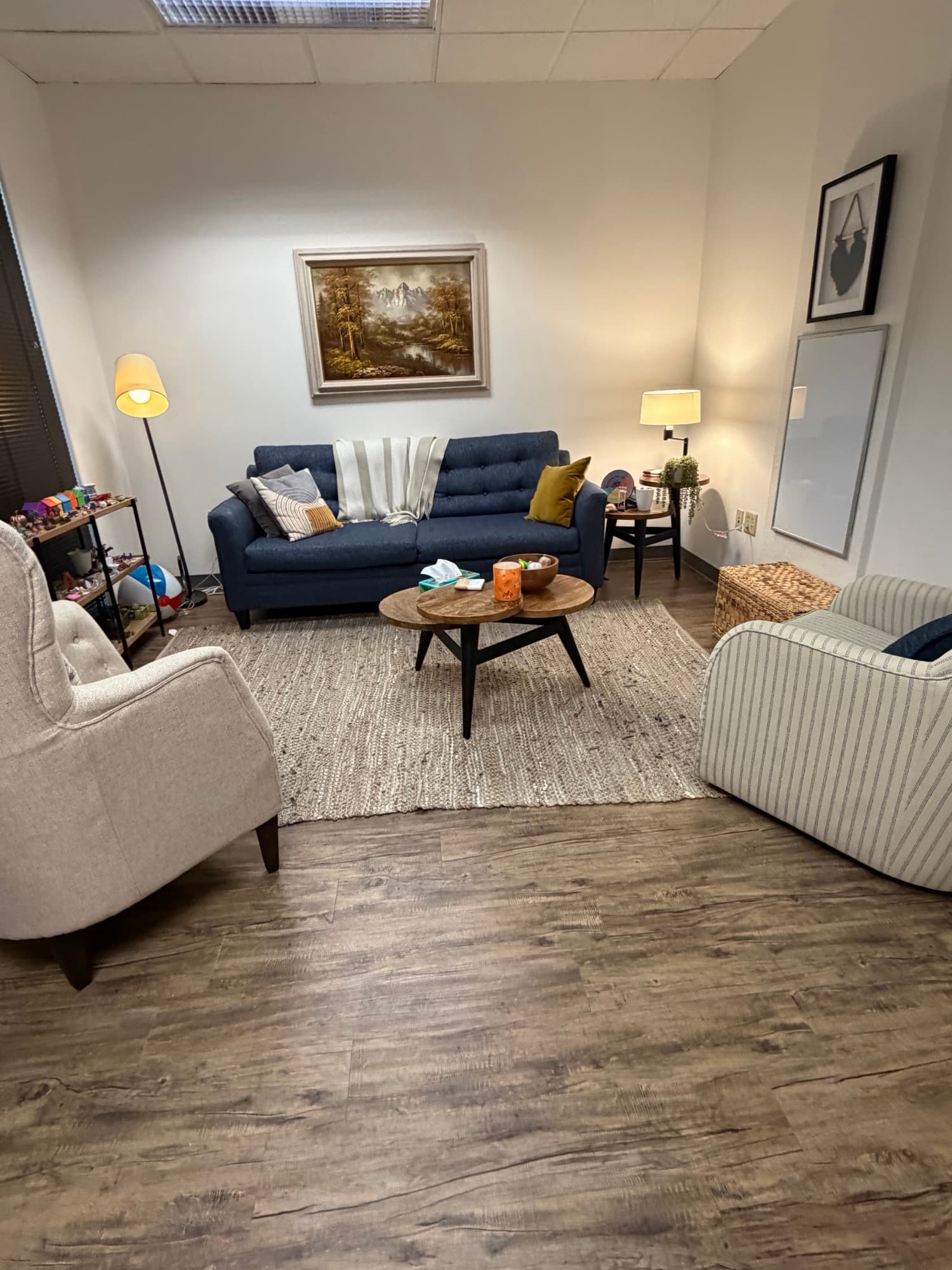 Therapy room with a tufted navy sofa and striped armchair