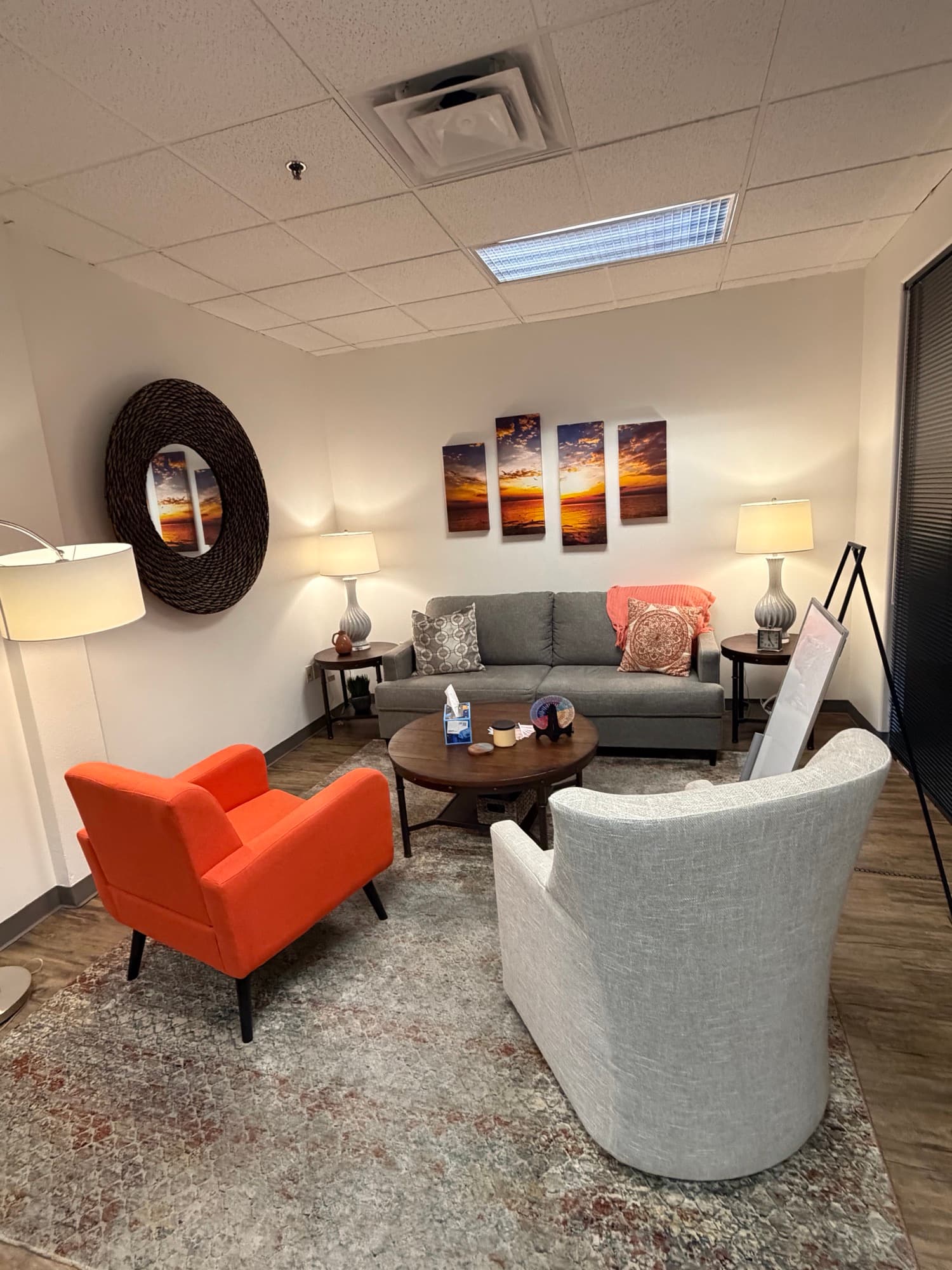 Therapy room with sunset photography and an orange accent chair